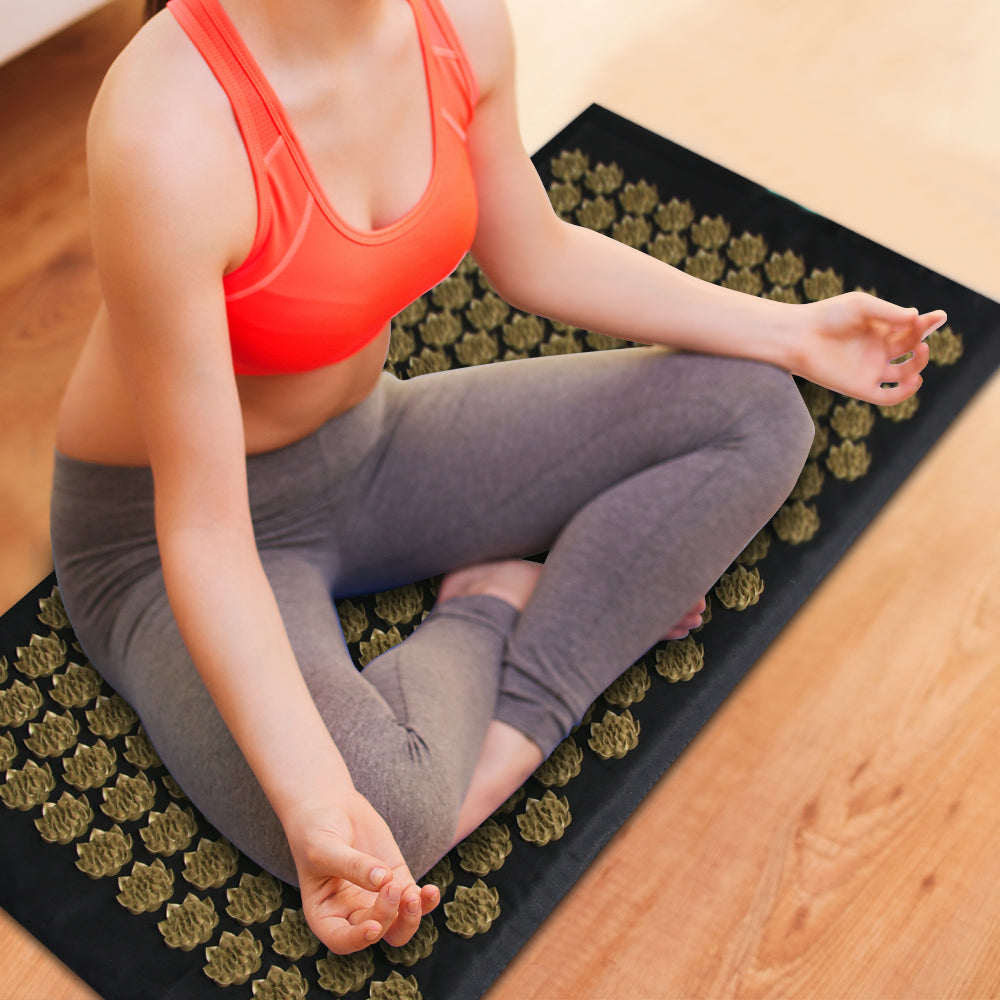 Acupressure Mat - home office health - a woman meditates on the black and gold mat